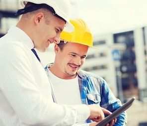 business, building, teamwork, technology and people concept - smiling builders in hardhats with tablet pc computer outdoors