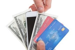 Hand holding banknotes credit cards and a tablet